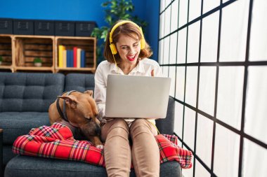 Genç ve güzel bir kadın kanepeye oturmuş kendini göstererek mutlu ve gururlu bir şekilde gülümsüyor. 