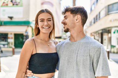 Genç İspanyol çift mutlu bir şekilde gülümsüyor ve şehirde birbirlerine sarılıyorlar..