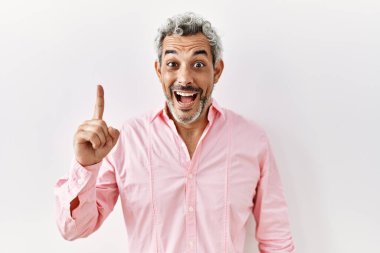 Orta yaşlı İspanyol bir adam izole edilmiş arka planda durup başarılı bir fikri işaret ediyor. Heyecanlı ve mutlu. Bir numara.. 