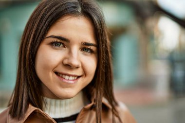 Genç, güzel, esmer kadın dışarıda mutlu bir şekilde gülümsüyor.