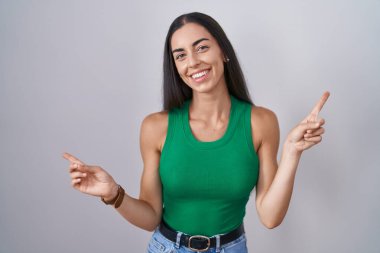 Young woman standing over isolated background smiling confident pointing with fingers to different directions. copy space for advertisement 