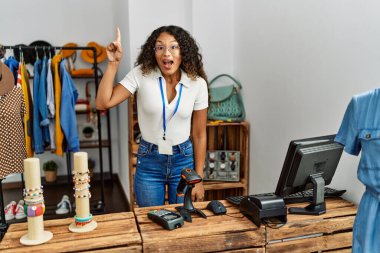 Giyim mağazasında çalışan güzel İspanyol kadın başarılı bir fikirle işaret ediyor. Heyecanlı ve mutlu. Bir numara.. 