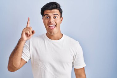 Mavi arka planda duran İspanyol adam başarılı bir fikir işaret ediyor. Heyecanlı ve mutlu. Bir numara.. 