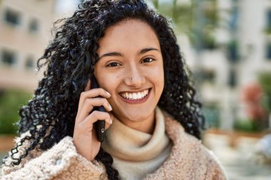 Genç İspanyol kadın gülümsüyor. Kendine güveniyor. Akıllı telefondan konuşuyor.
