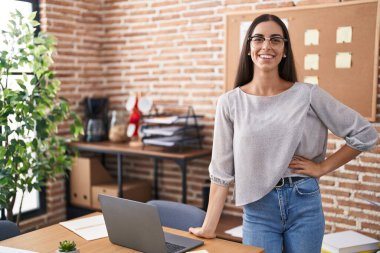 Genç, güzel, İspanyol bir iş kadını. Ofiste kendinden emin bir şekilde gülümsüyor.