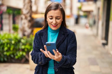 Sokakta akıllı telefon kullanan orta yaşlı bir iş kadını.