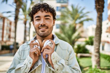 Yakışıklı, sakallı, neşeli, güneşli bir günde kulaklık takan bir İspanyol.