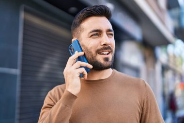 Genç İspanyol adam gülümsüyor. Kendine güveniyor. Sokakta akıllı telefondan konuşuyor.