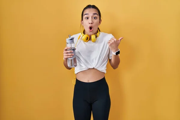 Ung Sydasiatisk Kvinna Bär Sportkläder Dricksvatten Förvånad Pekar Med Handen — Stockfoto