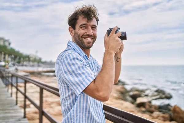 Joven Hombre Hispano Sonriendo Feliz Usando Cámara Playa —  Fotos de Stock