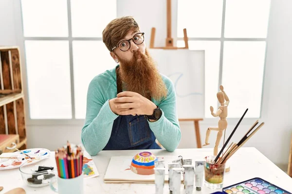 在艺术工作室里 红头发的男人留着长胡子 画着黏土碗 用嘴唇 疯狂和滑稽的姿势做鱼脸 有趣的表达方式 — 图库照片