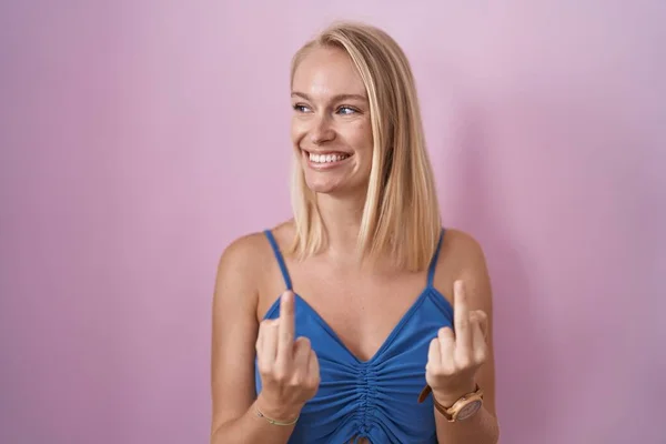 Молода Біла Жінка Стоїть Над Рожевим Тлом Показує Середній Палець — стокове фото