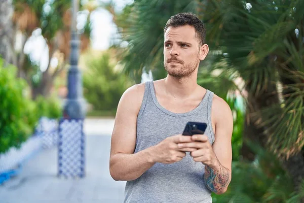 Jovem Hispânico Homem Usando Smartphone Com Expressão Séria Parque — Fotografia de Stock