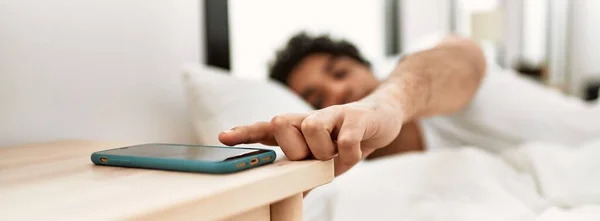 Jovem Hispânico Desligando Alarme Smartphone Deitado Cama Quarto — Fotografia de Stock