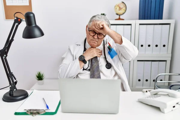 Senior Kaukasische Man Draagt Doktersuniform Stethoscoop Kliniek Die Het Voorhoofd — Stockfoto