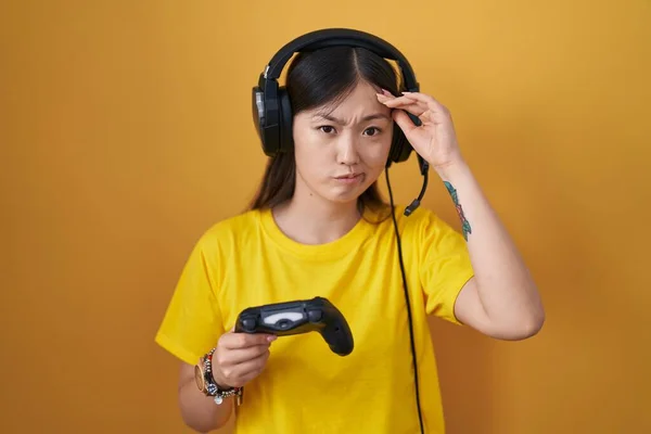 中国的年轻女子在玩电子游戏时 牵着控制器 担心并强调了自己的额头 紧张和对危机的焦虑 — 图库照片