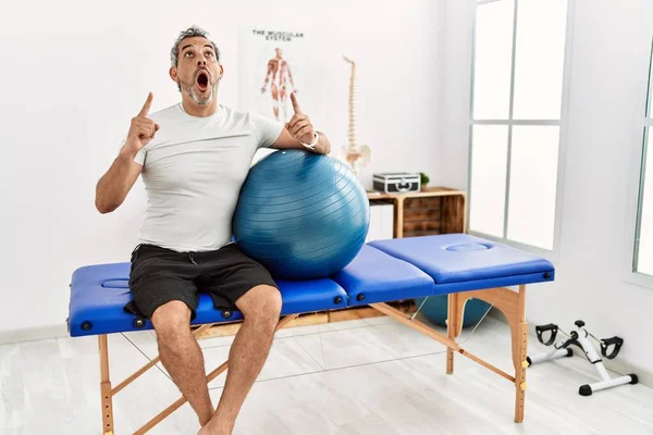 Latynos Średnim Wieku Klinice Rekonwalescencji Bólu Trzymając Pilates Piłkę Zdumiony — Zdjęcie stockowe