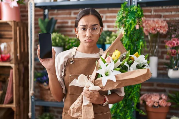 Mladá Hispánka Pracující Květinářství Ukazující Obrazovce Smartphonu Skeptickou Nervózní Mračí — Stock fotografie