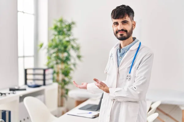 Jonge Spaanse Man Doktersuniform Doet Welkomstgebaar Met Handen Kliniek — Stockfoto