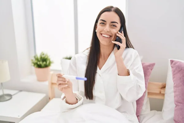 Junge Hispanische Frau Spricht Auf Dem Smartphone Und Hält Schwangerschaftstest — Stockfoto