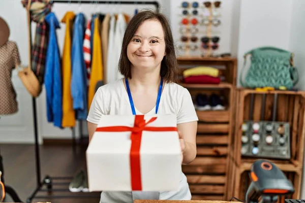 Brunette woman with down syndrome working as shop assistant wrapping gift at retail shop