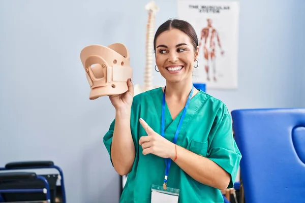 Mujer Hispana Joven Sosteniendo Cuello Cervical Clínica Sonriendo Feliz Señalando —  Fotos de Stock