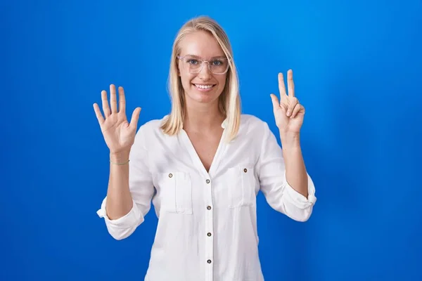 Mladá Běloška Stojící Nad Modrým Pozadím Ukazující Ukazující Prstem Číslo — Stock fotografie