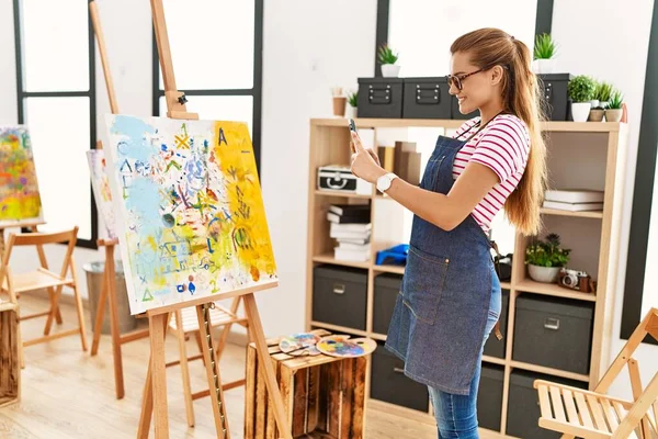 年轻女子面带微笑 自信地用智能手机在艺术工作室拍照 — 图库照片