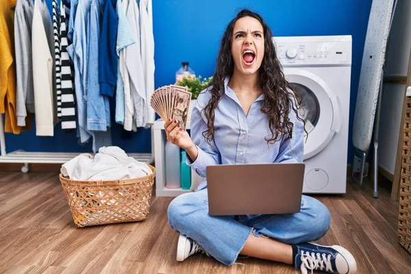 Young Brunette Woman Doing Laundry Using Laptop Holding Money Angry — ストック写真