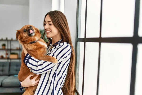 Young hispanic woman smiling confident hugging dog standing at home