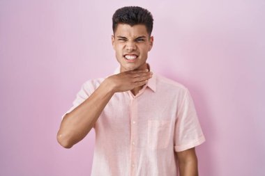 Pembe arka planda dikilen genç İspanyol adam bıçakla boğazı kesiyor, saldırganlığı şiddetle tehdit ediyor. 