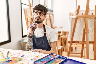 Resim stüdyosunda sakallı, çenesi çenesinde soru soran, düşünceli bir İspanyol. Düşünceli bir yüzle gülümsüyor. şüphe kavramı. 