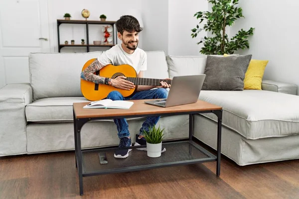 Jovem Hispânico Tocando Guitarra Clássica Usando Laptop Casa — Fotografia de Stock