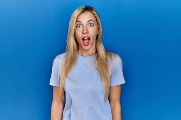 Piękna Blondynka Ubrana Luźną Koszulkę Niebieskim Tle Przestraszona Zszokowana Zaskakującą — Zdjęcie stockowe