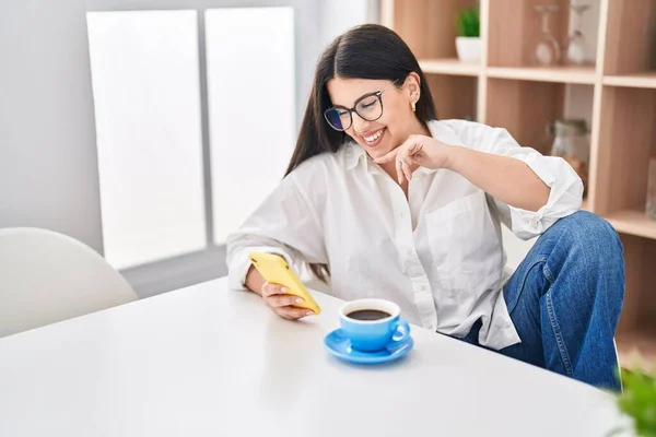 Young Hispanic Woman Using Smartphone Drinking Coffee Home — Stok fotoğraf