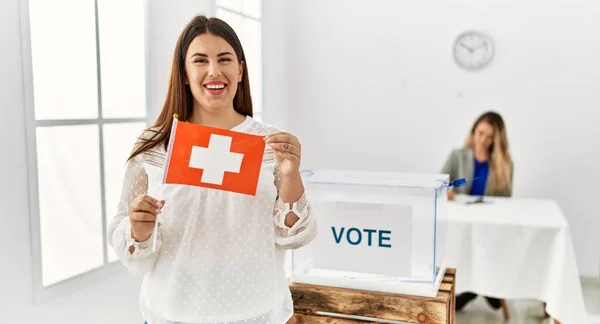 Young swiss voter woman smiling happy holding switzerland flag at electoral college.