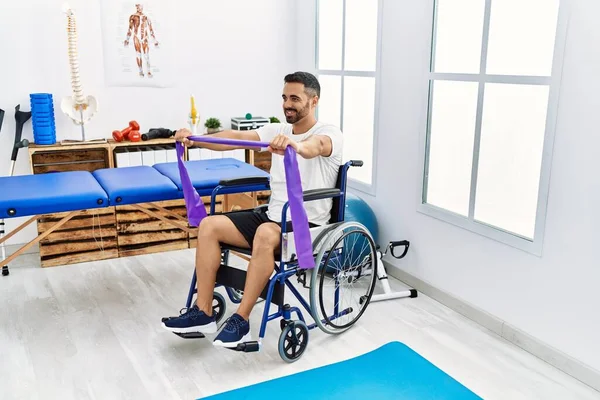 Junger Hispanischer Mann Bei Reha Behandlung Mit Gummiband Rollstuhl Klinik — Stockfoto