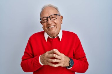 İzole edilmiş arka planda gri saçlı yaşlı adam el ele tutuşup gülümseyerek gevşemiş ve neşeyle gülümsüyor. Başarı ve iyimserlik 