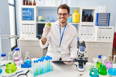 Laboratuvarda elma tutan genç İspanyol bilim adamı.