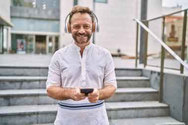 Şehirde akıllı telefon kullanan orta yaşlı bir adam.