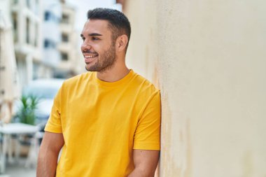 Young hispanic man smiling confident looking to the side at street