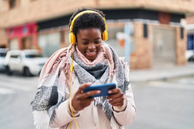 Afro-Amerikalı kadın gülümsüyor. Sokakta oyun oynarken kendine güveniyor.