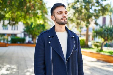 Genç İspanyol bir adam parkta ciddi bir ifadeyle yan tarafa bakıyor.