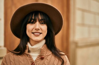 Açık havada gülümseyen, kışlık şapkalı esmer kadın.