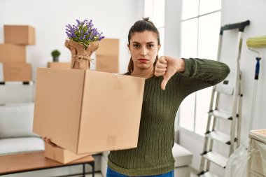 Genç İspanyol kadın elinde karton kutuyla kızgın bir yüzle hareket ediyor. Negatif işaret baş parmakları aşağıda, reddedilme konsepti ise... 