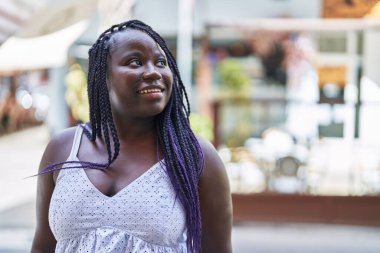 Afro-Amerikalı kadın gülümsüyor. Kendine güveniyor. Gökyüzüne bakıyor.