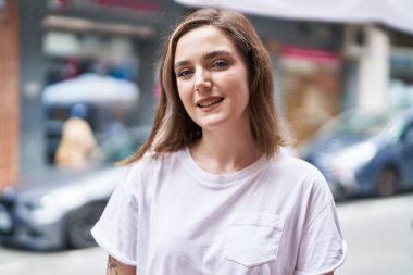 Sokakta kendinden emin gülümseyen genç bir kadın