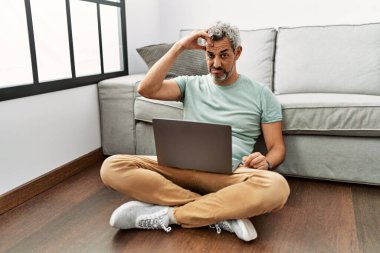 Orta yaşlı İspanyol bir adam oturma odasında dizüstü bilgisayar kullanıyor. Alnındaki sorun yüzünden endişeli ve stresli. Kriz için endişeli. 