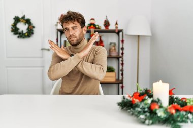 Masada sakallı genç yakışıklı bir adam oturuyor. Yılbaşı süslemeleri reddediliyor. Kollarını kavuşturuyor. 