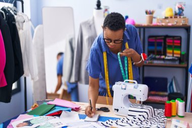 Terzi dükkanında dizüstü bilgisayar kullanarak gülümseyen Afro-Amerikan kadın terzi.